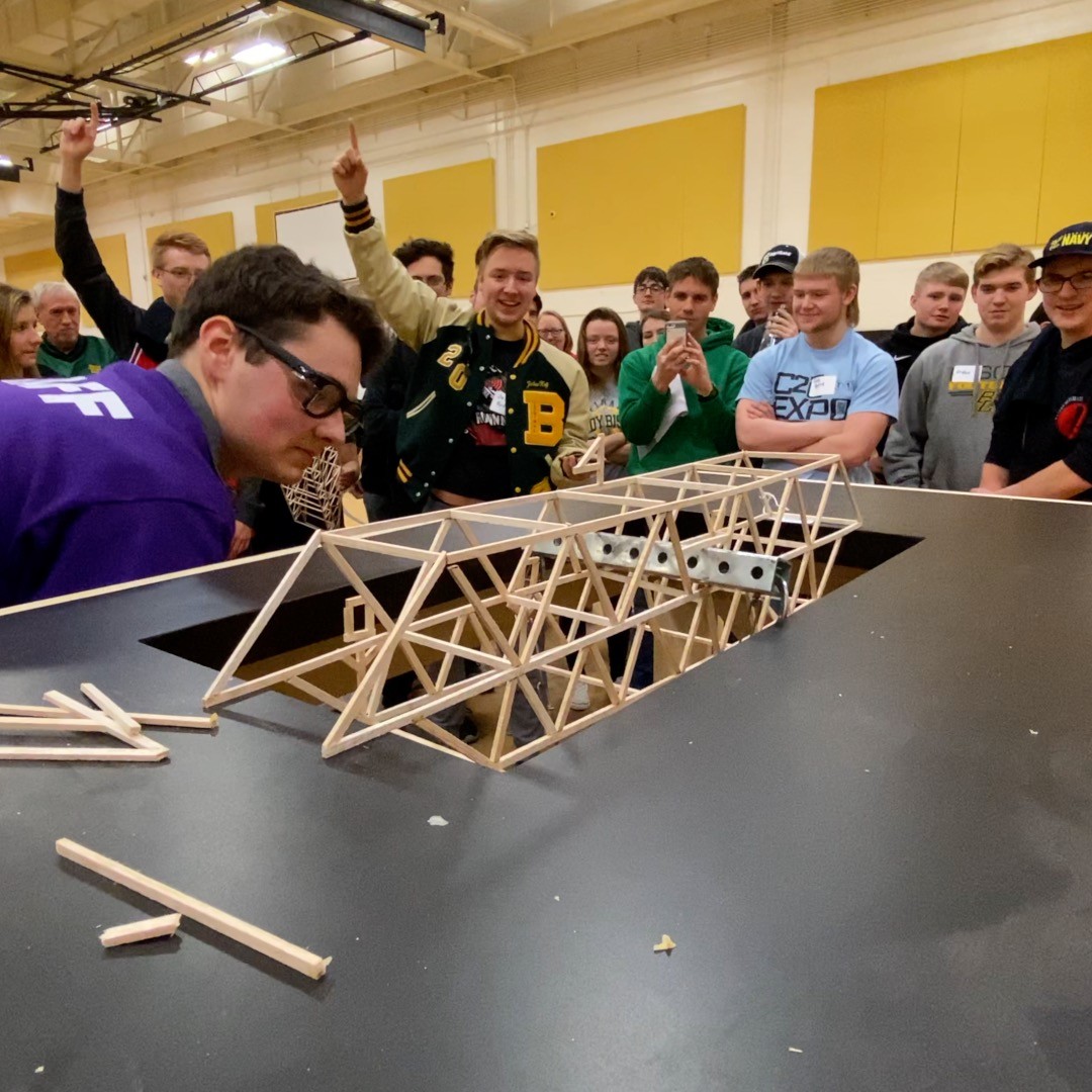 Balsa wood bridge being tested with student observing